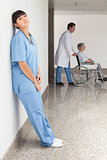 Tired nurse leaning against wall