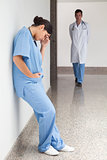 Sad nurse leans against wall