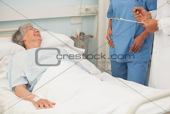 Elderly female patient smiling up at nurse and doctor