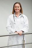 Female doctor smiling and leaning against railing