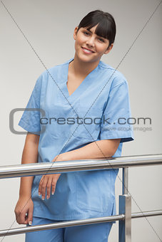 Nurse smiling while leaning against railing