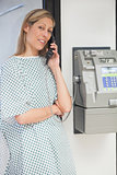 Sick woman smiling and using payphone