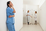 Nurse looking up and leaning against wall