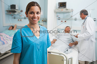 Happy nurse standing in hospital room