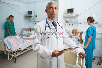 Doctor with folder in busy hospital room