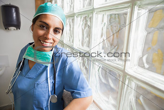 Happy nurse leans against glass wall