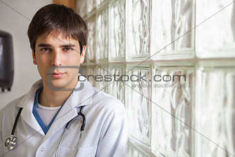 Doctor leans against glass wall