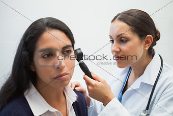 Doctor is looking into the ear of the woman