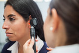 Doctor using otoscope to check woman's ear