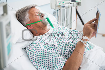 Patient is lying in bed reading in hospital ward