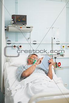 Man in oxygen mask reading in bed