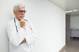 Doctor leaning against wall in corridor and thinking