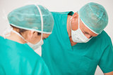 Two surgeons looking down on patient