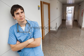 Nurse is leaning on the wall on the corridor and thinking