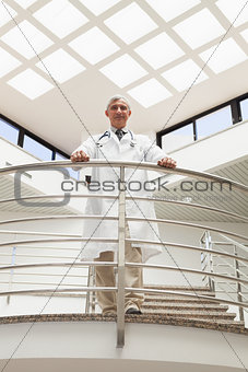 Doctor standing an the railing at the corridor looking down