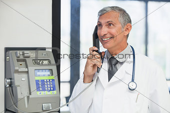 Doctor on a payphone and smiling in hospital