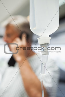 Intravenous drip with patient on phone in background