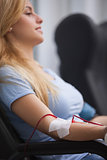Smiling woman getting a transfusion and sitting on a chair