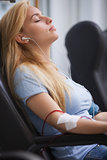 Woman donating blood and listening to music device