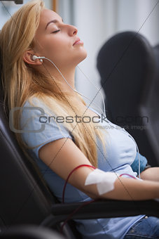 Woman donating blood and listening to music device