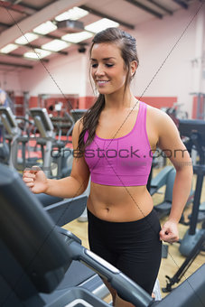 Happy woman running on a treadmill in a gym