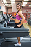 Smiling woman running on a treadmill in the gym