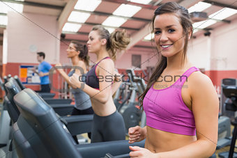 Smiling woman on a treadmill in the gym with people