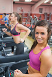 Women running on a treadmill in a gym smiling