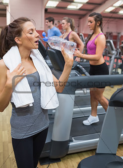 Woman drinking bottle of water in the gym