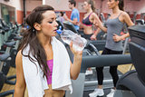 Woman drinking water beside treadmill