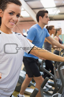 Smiling woman with other people stepping on  step machines