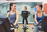 Two women talking while training in a spinning class