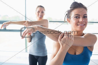 Two women stretching their arms