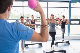 Trainer teaching his aerobics class while lifting weights