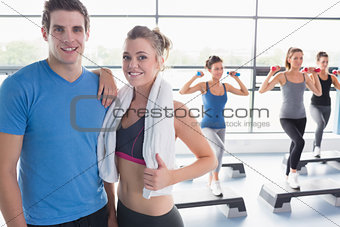 Trainer and woman smiling together while aerobics class taking place