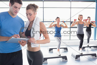 Women doing aerobics while trainer talking to woman