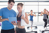 Trainer and woman talking while aerobics class lifting weights