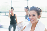 Women talking while another drinking water in fitness studio
