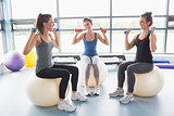 Three women lifting weights on exercise balls