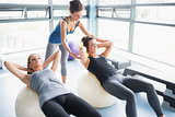 Women doing sit-ups on exercise balls in gym