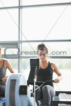 Two women training on row machines