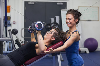 Female trainer teaching woman lifting weights