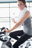 Woman riding an exercise bike and drinking water