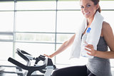 Woman holding a bottle and riding an exercise bike