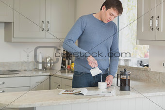 Man pouring milk into coffee