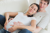Pregnant woman and husband lying on couch