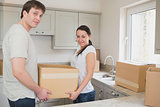 Young couple in the kitchen holding moving boxes