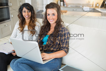 Happy girls using laptop for homework