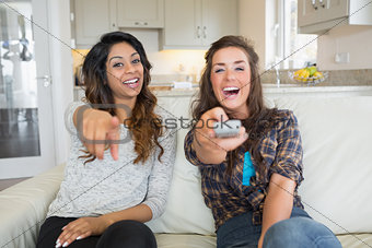 Two women smiling and laughing at television