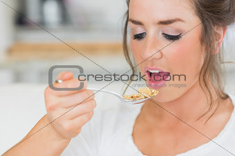 Girl lifting spoon of cereal to mouth